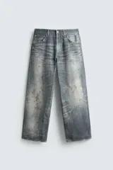 Pantalón de jean azul con efecto lavado y estampado, corte holgado y amplio en toda la pierna, tiro medio, cinco bolsillos y cierre frontal con cremallera y botón.