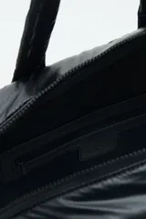 Bolso marrón con diseño matelassé, doble asa corta, correa larga desmontable y dos bolsillos frontales. Incluye llavero de corazón y dijes desmontables.