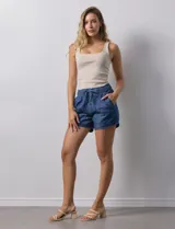 Short color beige de tencel, con pretina ancha elastizada y lazo de ajuste. Tiene bolsillos delanteros y bolsillos simulados en la parte trasera.