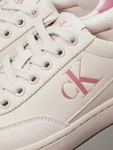 Zapatillas bajas Calvin Klein Jeans color crema con logo CK rosado en el lateral y detalle rosado en el talón.