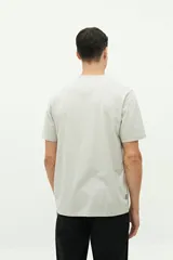 Remera azul de manga corta con cuello redondo y estampado de playa con sombrilla, reposera, balde y pala.