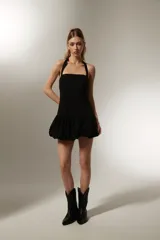 Vestido mini negro sin mangas de algodón, con cuello recto, corte ajustado y falda con volados.