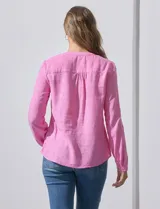 Blusa rosa de lino marca Zac & Rachel, con cuello a la base, escote en V y abertura central con botones. Tiene bolsillos delanteros y mangas largas regulables con presilla y botón.