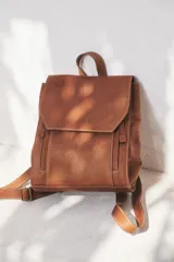 Mochila de cuero color marrón con cierre de solapa y hebilla, tamaño mediano.