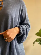 Blusa celeste de lino con escote en V con doble lazo y mangas largas con elástico en los puños.