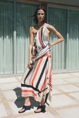 Falda midi de tiro medio con estampado de rayas rojas, negras y blancas. Tiene bajo asimétrico y cierre frontal tipo pareo ajustable con lazos negros.