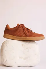 Zapatillas bajas de gamuza celeste con cordones y pañuelos estampados atados a los cordones.