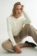 Cardigan tejido color crema con botones al frente y cuello redondo.