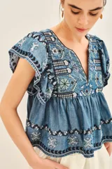 Camisa celeste de corte amplio confeccionada en tencel, con mangas cortas y ruedo con terminación de volado.