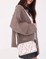 Bandolera negra de cuerina con doble compartimento con cierre y charm lateral. Tiene correa regulable y desmontable.