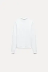 Camiseta blanca de manga larga con cuello alto y corte ajustado.