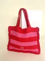 Bolso tipo tote tejido a crochet a mano, con hilo 100% algodón, con rayas horizontales rojas y rosadas. Cuenta con manija reforzada y grifa de acrílico Cilento.