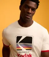 Remera de algodón color crema con cuello redondo y mangas cortas con ribete rojo. Estampa frontal con el logo de Kodak.