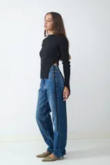 Pantalón de jean de tiro medio, corte recto, con diseño clásico de cinco bolsillos, cierre de cremallera y botón metálico.