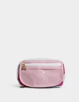 Cartuchera rectangular de tela estampada multicolor con divisiones internas, bolsillo frontal de PVC transparente con estampado de ositos y cierre con cremallera. Incluye un dije metálico con forma de moño.