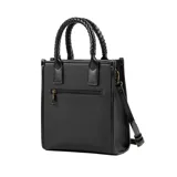 Cartera chica negra de cuero sintético con asas trenzadas fijas y correa regulable extraíble. Tiene cierre superior, un bolsillo interno con cierre, un bolsillo interno abierto y un bolsillo externo con cierre.