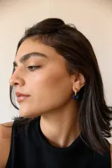 Aros de acero quirúrgico hipoalergénico con piedras naturales azules. Diseño de aro con dije circular colgante.