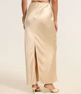 Vestido largo de satén color crema, con escote halter, espalda descubierta y abertura frontal. Presenta detalles de pedrería en el escote.