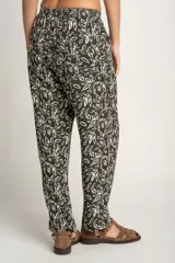 Pantalón recto con estampado de hojas color blanco sobre fondo negro, con cintura elástica y bolsillos laterales.