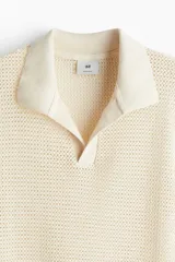Remera polo de manga corta color crema, con tejido de malla tipo crochet, cuello clásico y abertura en V.