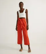 Pantalón clochard color naranja, con cintura elástica, cinturón para atar, cierre por cremallera, pliegues delanteros y barra doblada.