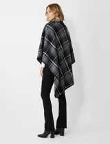 Capa corta de tejido grueso, color verde esmeralda con diseño de cuadros escoceses en azul marino y líneas finas en beige. Posee cuello alto que se cruza al frente y se cierra con un broche oscuro.