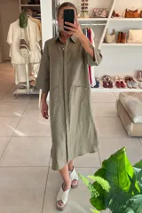 Vestido camisero midi color verde oliva, de lino, con cuello camisero, manga 3/4, cierre frontal con botones y bolsillos de parche.