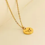 Collar dorado con dije redondo con el signo de Aries grabado.