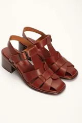 Sandalias plateadas de cuero con tiras entrecruzadas y hebilla lateral. Taco de madera de 6 cm.
