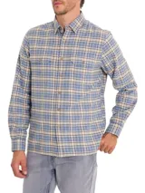 Camisa de franela a cuadros azul, beige y negro, de manga larga con puños abotonados, cuello camisero y cierre frontal con botones de madera. Tiene dos bolsillos de parche con botón en el pecho. Confeccionada en algodón orgánico cepillado.