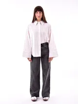 Camisa blanca a rayas verticales color ladrillo, de corte recto y mangas largas con puños abotonados.