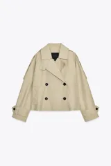 Trench corto color beige confeccionado en mezcla de algodón. Diseño cruzado con doble botonadura, cuello con solapa de muescas ajustable, manga larga con trabillas en hombros y bolsillos delanteros.