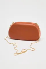 Bolso marrón con forma de caja, con cierre dorado en forma de C y asa de cadena dorada para usar como bandolera.