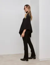 Poncho tejido color negro, con cuello polera y diseño de trenzas diagonales en el frente. Presenta un corte asimétrico en el ruedo.