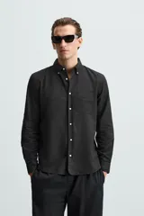 Camisa celeste a rayas verticales, de corte relaxed fit, confeccionada en lino y algodón. Tiene cuello abotonado, manga larga con puños abotonados, bolsillo de parche en el pecho y cierre frontal con botones.