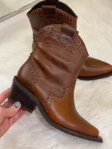 Botas cortas de cuero color marrón con punta fina, taco cuadrado y apliques de tachas metálicas.
