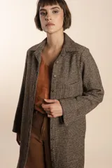 Camisa larga color crema con rayas verticales finas en gris, con botones dorados y bolsillo plaque en la delantera.