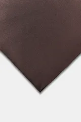 Top de escote recto y hombros descubiertos, confeccionado en tela satinada negra. Presenta un bajo asimétrico y cierre en la espalda con lazada.