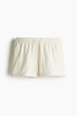 Short de baño color crema con textura de sirsaca, cintura elástica con cordón ajustable, bolsillos laterales, bolsillo trasero con cierre autoadherente y suspensor interior de malla.