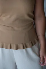 Musculosa de tejido de punto color tostado, con escote en V y borde inferior con detalle de ruedo o volado.