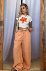 Remera blanca de algodón con estampado de flor naranja.