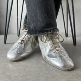 Championes urbanos plateados de cuero, con cordones y suela blanca.