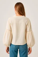 Blusa negra con escote en V con lazos, mangas largas abullonadas y puños elásticos.