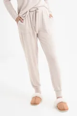 Conjunto de pantalón y remera de mangas largas color beige, de corte holgado. El pantalón tiene cintura elástica con cordón ajustable y bolsillos laterales.