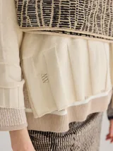 Buzo de punto color beige con diseño geométrico en negro. Incluye cuello alto y falda cruzada a juego.