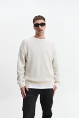 Buzo de punto color crudo, de corte oversize, con cuello redondo y puños.