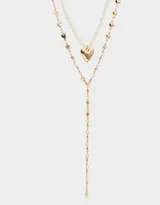Set de dos collares dorados: uno corto de perlas sintéticas con dije de corazón dorado y otro largo con cadena de eslabones y dijes de corazones.
