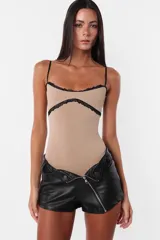 Short negro de cuerina con cierre diagonal desmontable, tiro medio y broches snap en el delantero.