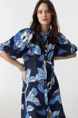 Vestido midi de lino azul marino con estampado floral en tonos celeste y blanco, cuello mao, mangas abullonadas hasta el codo y cierre frontal con botones de nácar.