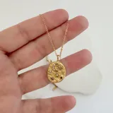 Collar dorado con dije ovalado texturizado con incrustaciones de circonitas en forma de luna creciente, ojo turco y estrellas de diferentes tamaños.